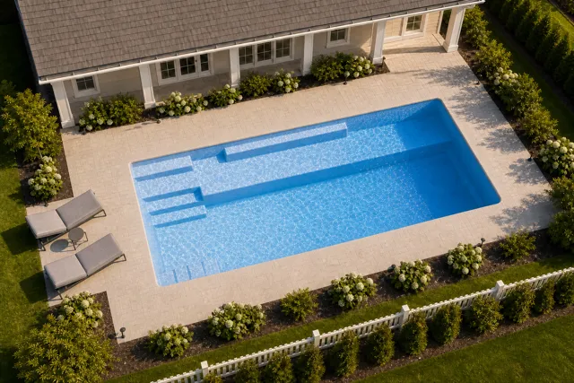 Daytime render of the Providence 14 fiberglass pool with cantilever coping and a Sapphire Blue interior, seen from above at an angle.