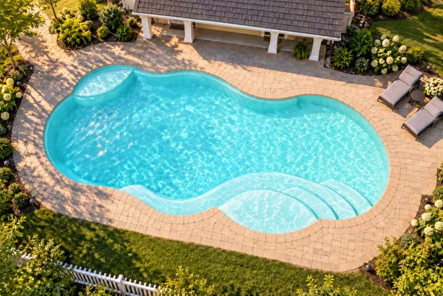 Daytime render of the Sun Day 1530 fiberglass pool with cantilever coping and a Arctic Shimmer interior, seen from above at an angle.