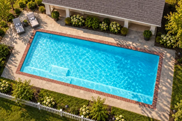 Daytime render of the The Marvelous 40 fiberglass pool with brick coping and a Coral Blue interior, seen from above at an angle.