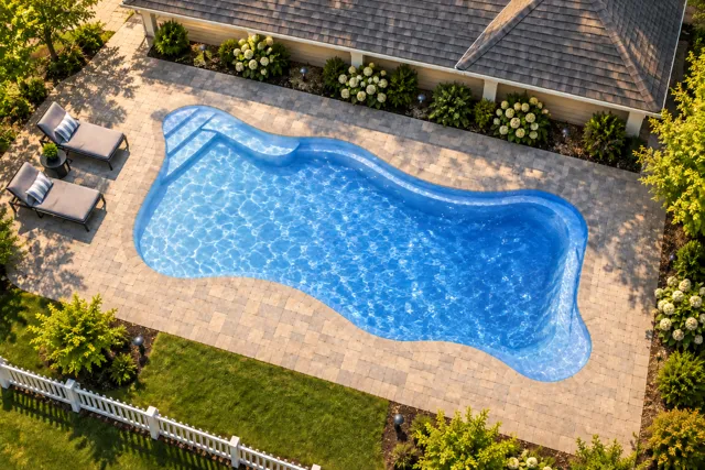 Daytime render of the Cape Cod 16 fiberglass pool with cantilever coping and a Sapphire Blue interior, seen from above at an angle.