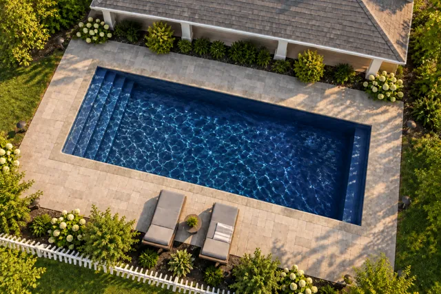 Daytime render of the Kingston fiberglass pool with stone coping and a Night Sky interior, seen from above at an angle.