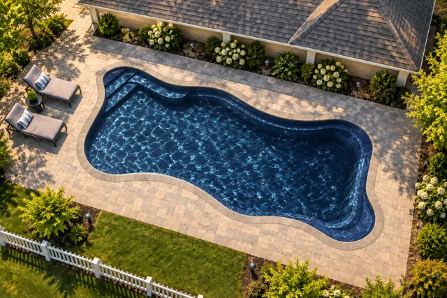 Daytime render of the Cape Cod 16 fiberglass pool with stone coping and a Night Sky interior, seen from above at an angle.