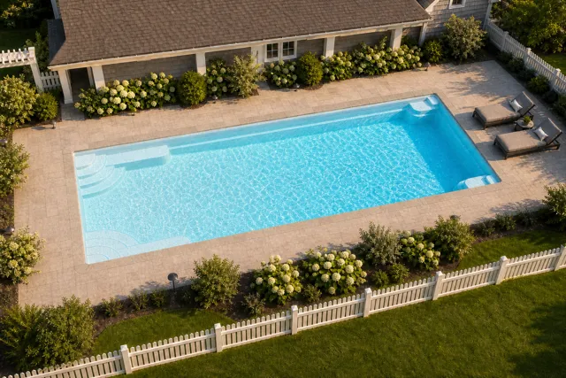 Daytime render of the Goliath 1641 fiberglass pool with stone coping and a Caribbean Sparkle interior, seen from above at an angle.