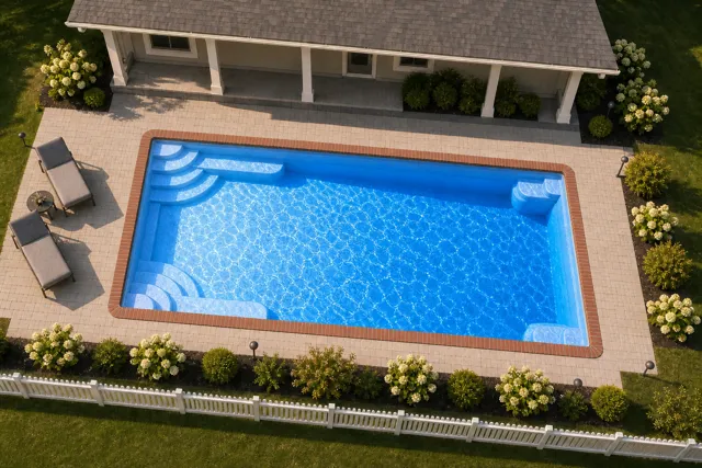 Daytime render of the Goliath 1633 fiberglass pool with brick coping and a California interior, seen from above at an angle.
