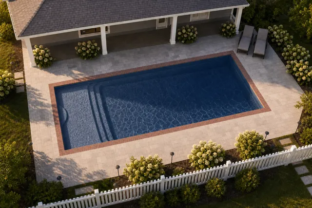 Daytime render of the Cayman 14 fiberglass pool with brick coping and a Ocean Blue interior, seen from above at an angle.