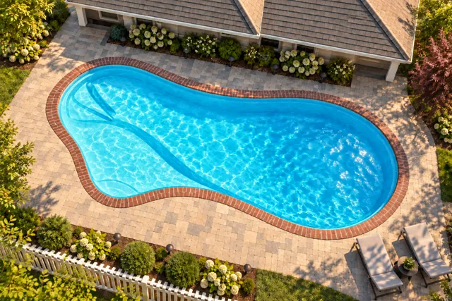 Daytime render of the The Inspiration 26 fiberglass pool with brick coping and a Coral Blue interior, seen from above at an angle.